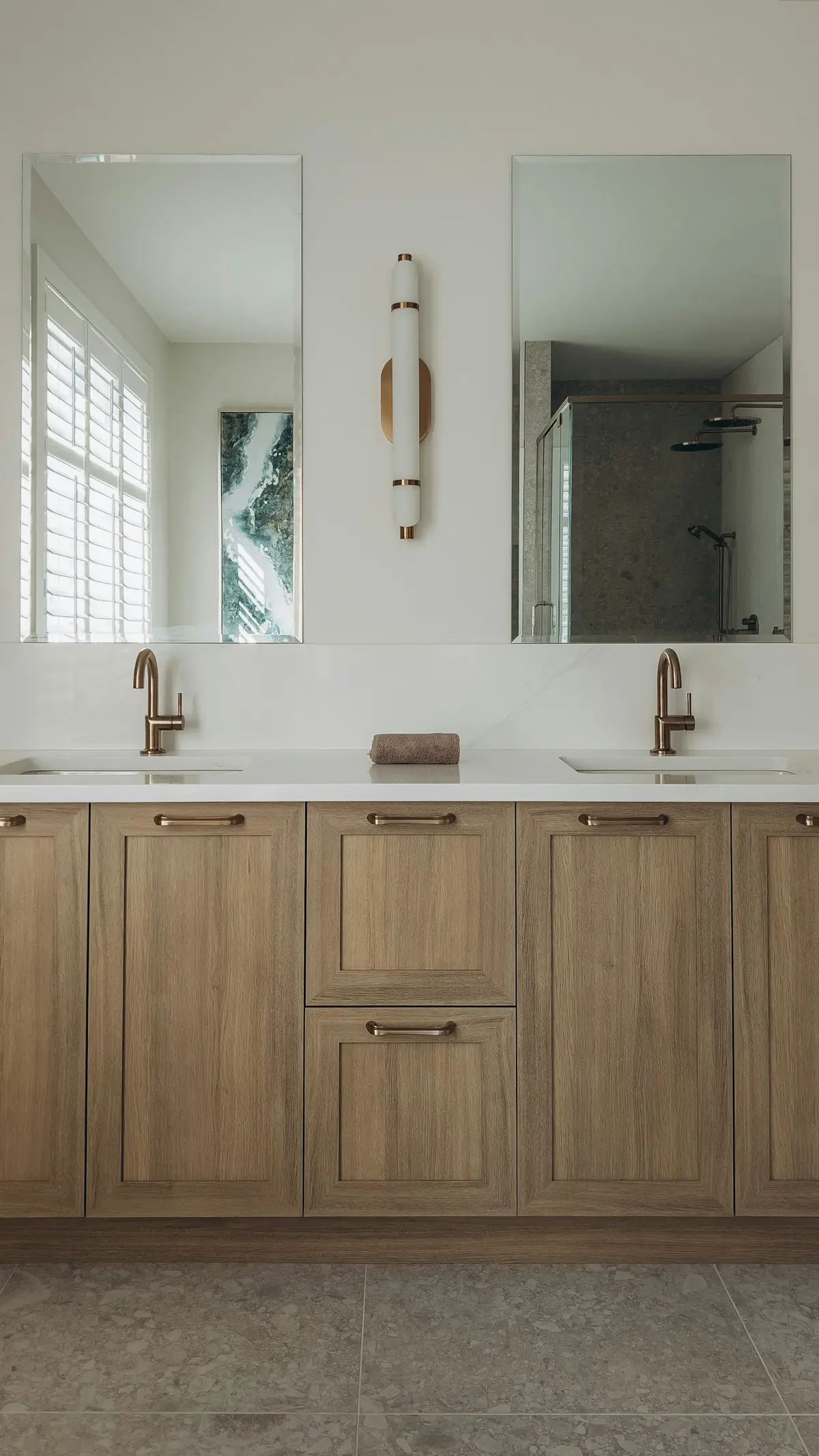 Oak shaker double vanity with brass faucets, frameless mirrors and a slim brass wall sconce